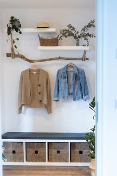 a coat rack with clothes hanging on it and baskets under the shelf next to it