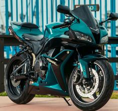 a blue motorcycle parked in front of a fence