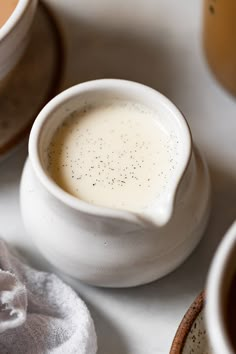 there is a small white bowl on the table next to other bowls and spoons