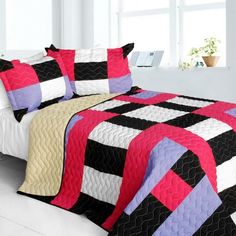 a black and white quilted bed with pink accents on the comforter is shown