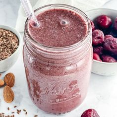 a smoothie in a mason jar surrounded by nuts and berries