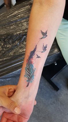 two people holding hands with tattoos on their wrists and one has a bird flying through the air