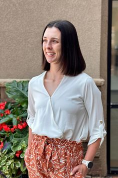 This not-so-basic blouse is a stylish and versatile top that features a wrap design with a crossover front. It has a flattering V-neckline and 3/4 sleeves with buttoned cuffs. Off-white color TTS Fit. Jess has this top tucked into our Lucia pants. 100% Polyester Basic Blouse, Basic Blouses, Off White Color, Crossover, White Color, Off White, Pants, White, Color