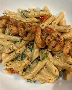 pasta with shrimp and spinach is served on a white plate, ready to be eaten