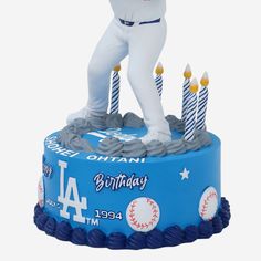 a baseball player figurine on top of a birthday cake with candles in it