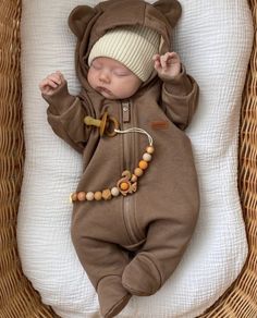 a baby sleeping in a brown bear outfit