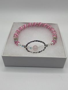 a pink beaded bracelet with a button on it in a white gift box for someone special