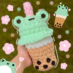 someone is holding up a crocheted ice cream cone with a frog on top