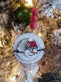 a snowman ornament hanging from a christmas tree