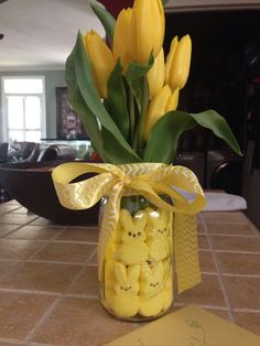 a vase filled with yellow flowers sitting on top of a tiled counter next to a note