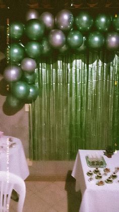 the balloons are hanging from the ceiling in front of the table and chair set up for a party