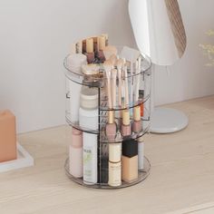 an organized makeup holder on a desk next to a mirror