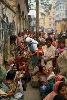 a large group of people are gathered together in an alleyway, some with bags on their heads