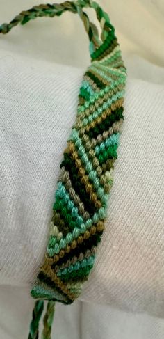 a close up of a green and brown bracelet on a person's arm wearing a white shirt