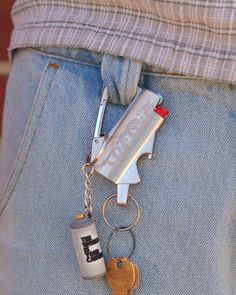 a person wearing jeans and holding a bottle with a keychain attached to it