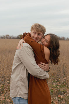 a man and woman hugging in the middle of a field