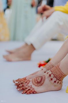 two feet with henna on them sitting next to each other in front of people