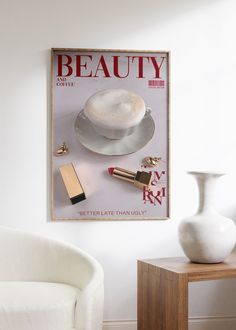 a white chair sitting next to a table with a vase on it and a magazine cover