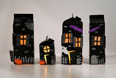 three black paper houses with bats and pumpkins on them, one has a ghost