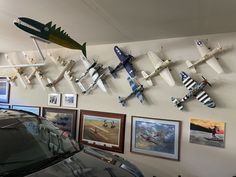 several airplanes are hanging on the wall above a car