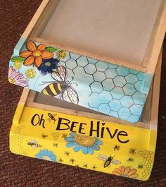 an open beehive box on the floor with bees and flowers painted on it