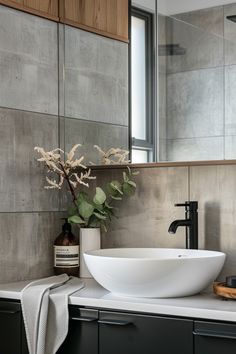 a white bowl sink sitting on top of a bathroom counter next to a wooden cabinet