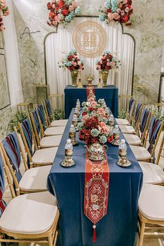 the table is set up with blue linens, gold chairs and vases on it