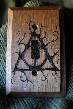 an intricately designed wooden switch plate cover on a green sweater with black and white stitching