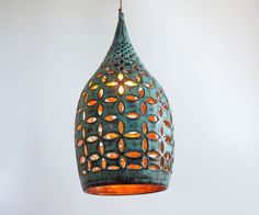 a green and orange light hanging from a ceiling fixture with an intricate design on it