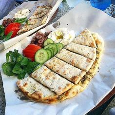 two trays filled with different types of food on top of white paper wrappers