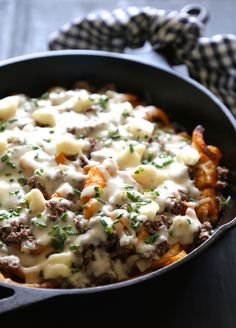 a casserole dish with cheese and meat in it sitting on a table next to a napkin