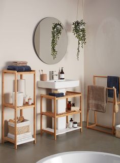 a white sink sitting under a mirror next to a wooden shelf