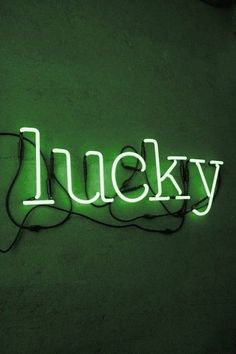 a neon sign that reads lucky on the side of a wall with wires attached to it