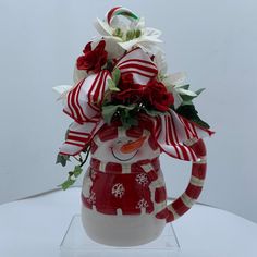 a red and white christmas mug with flowers in it's head, on a clear acrylic stand