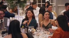 a group of people sitting around a table with wine glasses on it and smiling at the camera