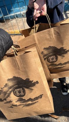 three brown bags with designs on them are being held by someone's hand as they walk down the street