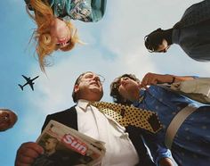 three people looking up at an airplane flying in the sky with their heads above them