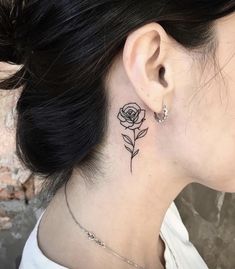 a woman's neck with a rose tattoo on her left side behind the ear