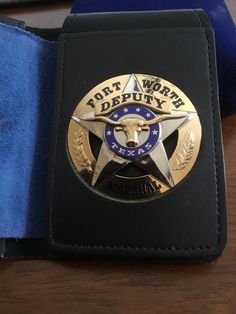 a black wallet with a sheriff badge on the front and blue velvet lining around it