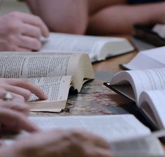 several people are sitting at a table with open books