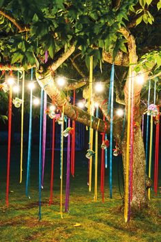 a tree with lights hanging from it's branches and some ribbons on the ground