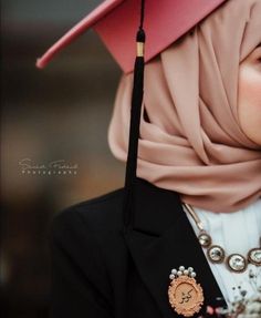 a woman wearing a pink hat and black jacket with pearls on her necklace, is looking at the camera