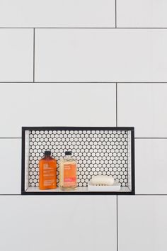 a white tiled wall with two bottles and soap on it