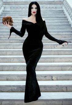 a woman in a black dress is walking down the stairs with a donut on her hand