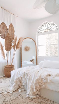 a bedroom with a bed, mirror and large plant in it's centerpiece