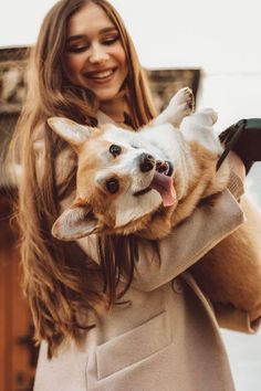 a woman holding a dog in her arms and smiling at the camera while she holds it up