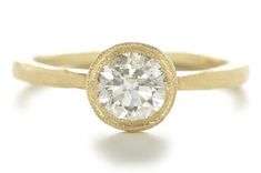 a yellow gold engagement ring with a round diamond in the center, on a white background