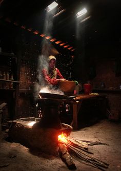 a man cooking food on top of a stove in a room filled with wooden planks