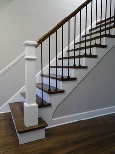 a white stair case with wooden handrails and wood flooring in a house