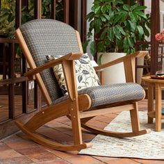 a rocking chair sitting on top of a brick floor next to a table with flowers